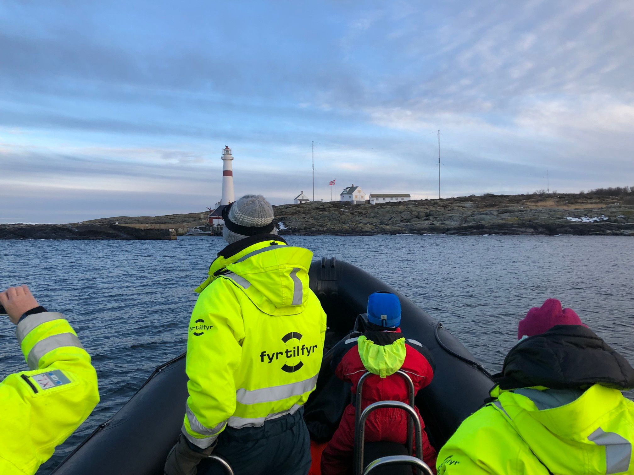 Passasjerer på RIB med fyr i bakgrunnen